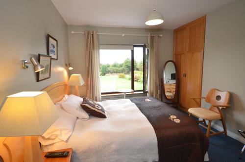 a bedroom with a bed with a lamp and a window at Gormans Country Home in Killarney