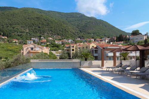 a swimming pool with a mountain in the background at Sun Village Aparthotel in Herceg-Novi