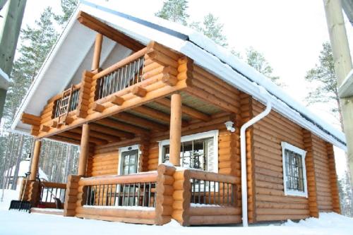 a log cabin with a deck in the snow at Villa Ainola in Sapsalampi