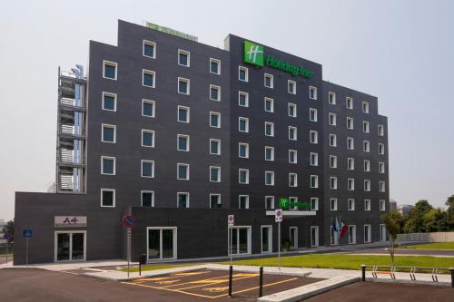 a large gray building with a green sign on it at Holiday Inn Milan Nord Zara by IHG in Cinisello Balsamo