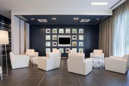 a waiting room with white chairs and a tv at Holiday Inn Milan Nord Zara by IHG in Cinisello Balsamo