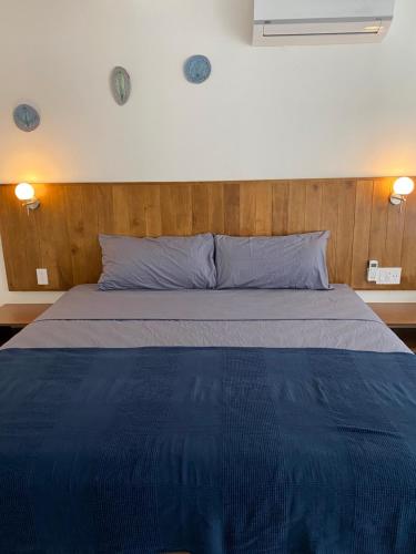 a bed in a bedroom with a blue blanket at Ride On! Surf Hotel in Nosara