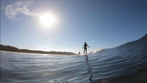 a person walking in the water on the beach at Ride On! Surf Hotel in Nosara