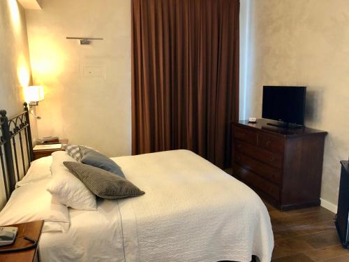 a bedroom with a white bed and a television at Hotel Ferro di Cavallo in Pavullo nel Frignano