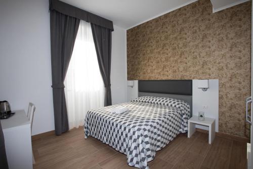 a bedroom with a bed with a checkered blanket and a window at Guesthouse Porto di Roma in Civitavecchia