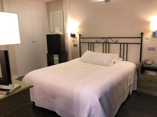 a bedroom with a white bed and a television at Hotel Ferro di Cavallo in Pavullo nel Frignano