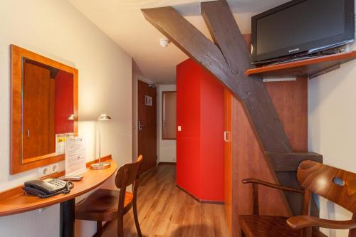 a room with a table with a tv on a wall at A-Train Hotel in Amsterdam