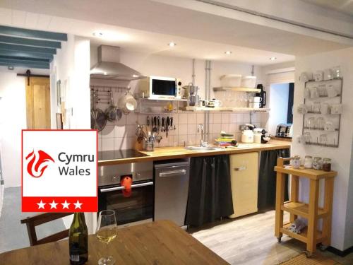 a kitchen with a table and a sign in it at Farmhand Cottage in Narberth