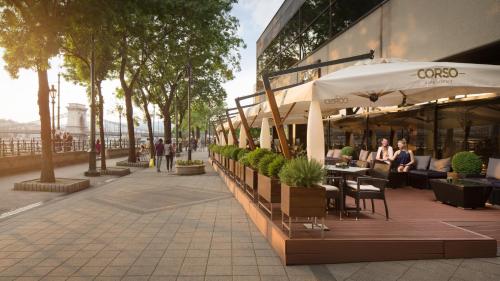 people sitting at tables with umbrellas outside of a building at InterContinental Budapest by IHG in Budapest
