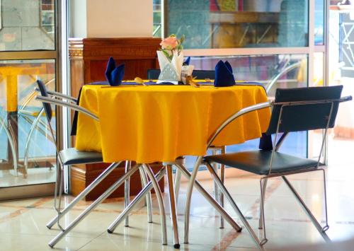 una mesa con sillas y un mantel amarillo en New Hotel Aquiline, en Arusha