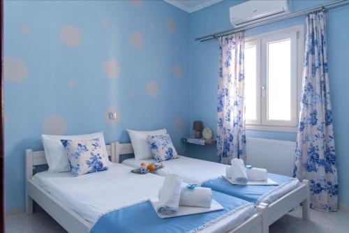 two beds in a room with blue walls and a window at Port View House in Parasporos