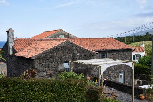 uma casa de pedra com uma tenda branca em frente em Villa 4 Seasons em São Roque do Pico