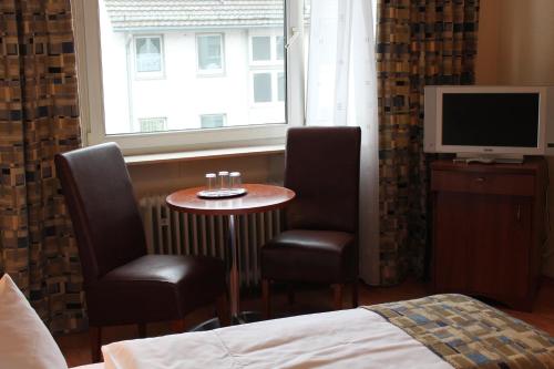 a bedroom with a table and two chairs and a window at City Hotel Frankfurt in Frankfurt/Main