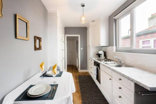 cocina con armarios blancos, fregadero y ventana en The Bluebird - One Bedroom Apartment in Watford, en Watford