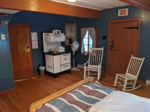 a bedroom with blue walls and a bed and two chairs at Auberge de jeunesse du Domaine à Liguori in Petite-Rivière-Saint-François