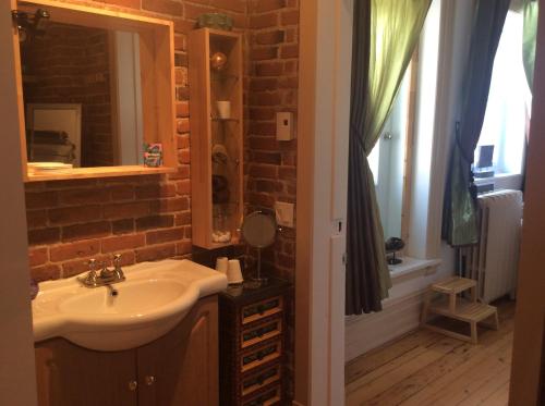 a bathroom with a sink and a brick wall at Île de Garde B&B in Sherbrooke