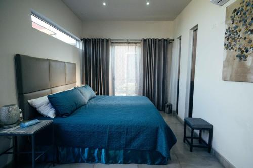 Un dormitorio con una cama azul y una ventana en Entre Vides Valle de Guadalupe en Valle de Guadalupe