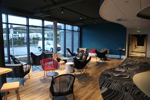 a room with chairs and tables and windows at ibis Budget Le Treport Mers Les Bains in Mers-les-Bains