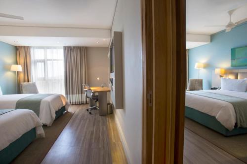 a hotel room with two beds and a desk at Holiday Inn Mauritius Mon Trésor by IHG in Blue Bay
