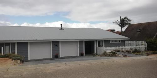 a house with white garage doors on a street at EEZY BREEZY HOLIDAY HOME in Knysna