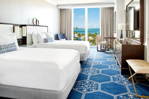 two beds in a hotel room with a view of the ocean at Fairmont El San Juan Hotel in San Juan