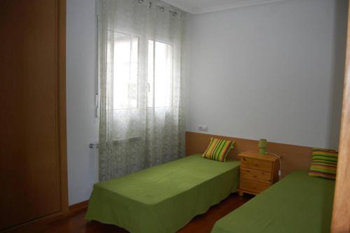a bedroom with two green beds and a window at La Casa de Lines in Monforte de Lemos