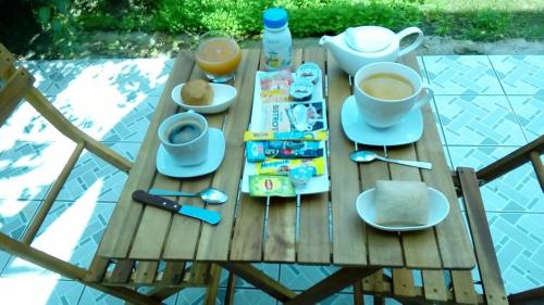 a wooden table with cups of coffee and food on it at Maison CÉCILIA in Port-Louis