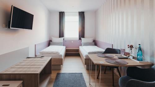 Cette chambre comprend 2 lits et une table. dans l'établissement Boardinghouse Sorgenfrei, à Hagen