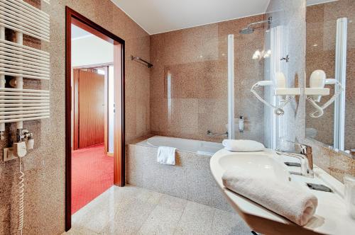 a bathroom with a tub and a sink and a shower at Grand Royal Hotel in Poznań