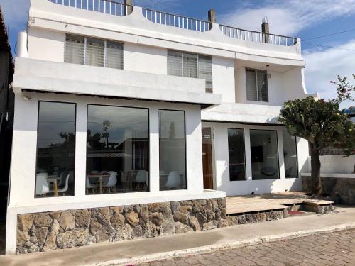 a white house with large windows and a stone wall at Cactus in Puerto Baquerizo Moreno