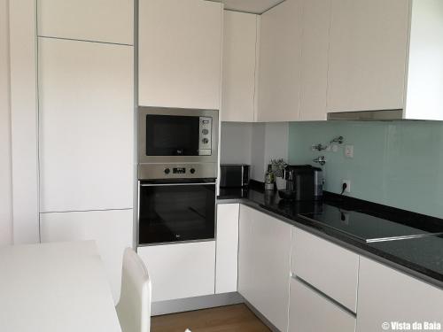 a kitchen with white cabinets and a microwave at Vista da Baia in Salir de Porto