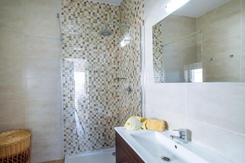 ein Bad mit einer Dusche, einem Waschbecken und einem Spiegel in der Unterkunft Apartment Isabel in Carvoeiro