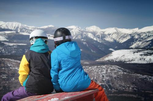 two people sitting on top of a snow covered mountain at Fairmont Hot Springs Resort in Fairmont Hot Springs