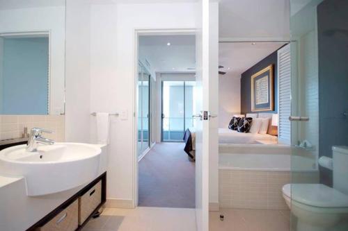 a bathroom with a sink and a toilet and a bedroom at 301 Harbour View in Cairns
