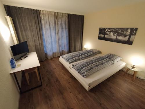 Schlafzimmer mit einem Bett und einem Schreibtisch mit einem Computer in der Unterkunft Motelina in Wattwil