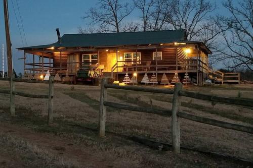 a wooden cabin in a field with a fence at The Christmas Cabin in Ozark