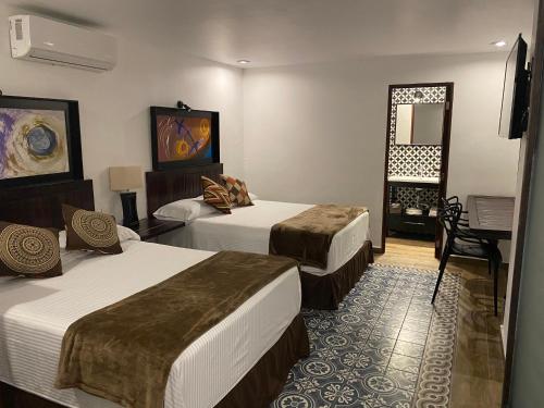 a hotel room with two beds and a mirror at Hotel Raices de Mar in Mazatlán