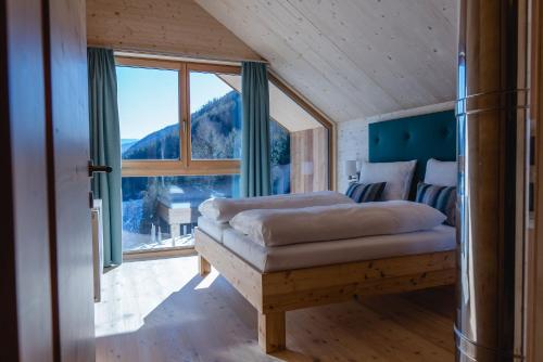 a bedroom with a bed and a large window at HOCHoben Chalets & Mobilhomes in Mallnitz