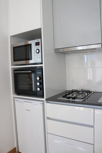 a white kitchen with a microwave and a stove at Artvilla Tourism Houses in Castanheira de Pêra