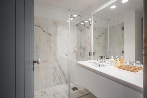 La salle de bains blanche est pourvue d'une douche et d'un lavabo. dans l'établissement Loja Sr Costa by Casas com Estória Boutique Houses, à Santa Comba Dão