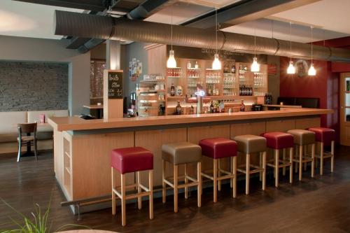 eine Bar in einem Restaurant mit roten Stühlen in der Unterkunft Troll's Brauhaushotel in Medebach