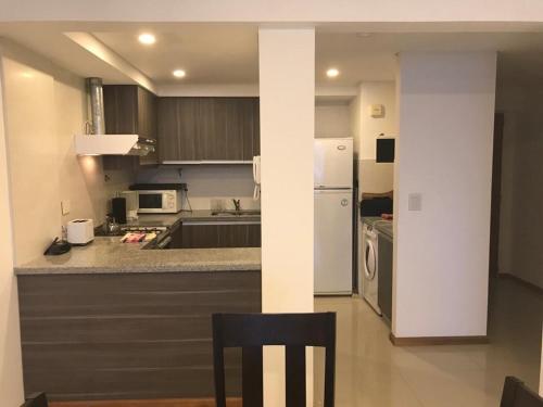 eine Küche mit einem weißen Kühlschrank und einem schwarzen Stuhl in der Unterkunft La mansa in Puerto Madryn