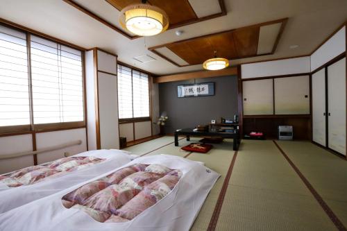 a bedroom with two beds and a table and windows at 楽奇温泉旅館 in Yamanouchi