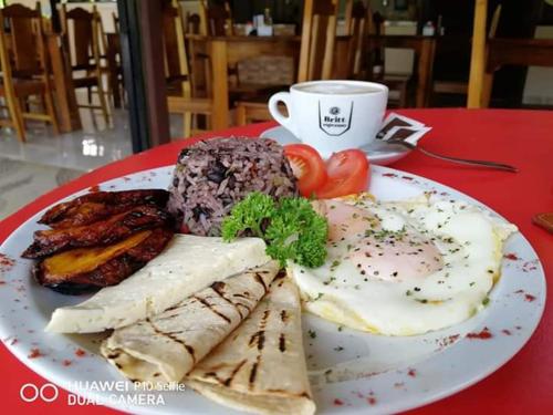 a plate of food with eggs and meat and a cup of coffee at Habitaciones el corral in Aguacate