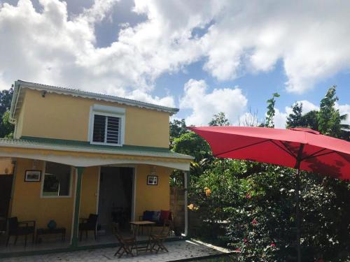 a red umbrella in front of a house at Maison CÉCILIA in Port-Louis