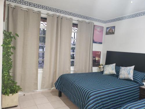 a bedroom with a bed with a blue and white striped blanket at Casa Zac Nicte Mx-Departamento BALAM in Cancún