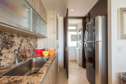 a kitchen with a sink and a refrigerator at Condo en Nuevo Vallarta con playa en Vidanta in Mezcales