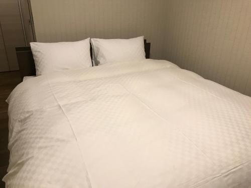 a white bed with white sheets and pillows at Kyo no yado en in Kyoto