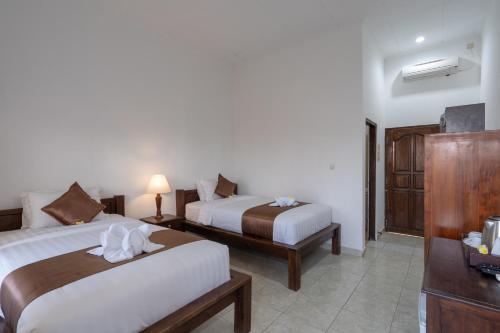 a hotel room with two beds and a television at Nusa Indah Bungalow in Nusa Lembongan