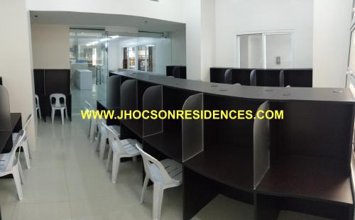 uma sala de espera com mesas pretas e cadeiras brancas em Jhocson Residences em Manila